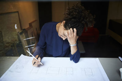 Female tensed architect working at table in office