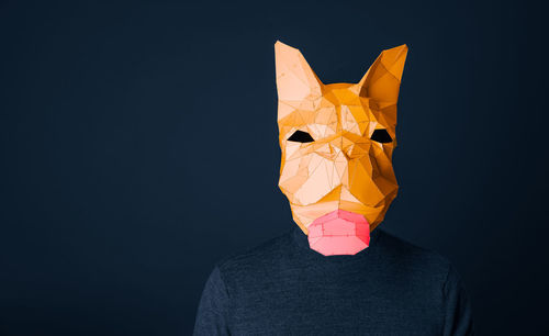 Person with french bulldog origami mask against blue background
