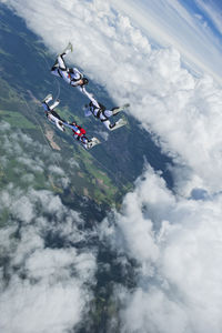 High angle view of people flying over mountain against sky