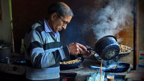 Side view of man pouring tea in glass cup