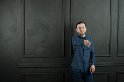 Portrait of young man standing by wall