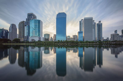 Reflection of buildings in lake against sky in city