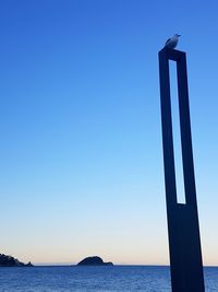 Low angle view of sea against clear blue sky