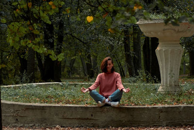 Portrait of young woman sitting on retaining wall