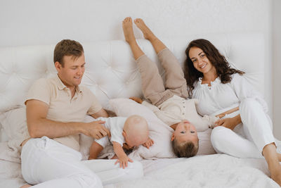 Family with two kids on the bed having fun. mather, father baby and toddler sons are happy 