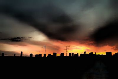 Silhouette of city against cloudy sky