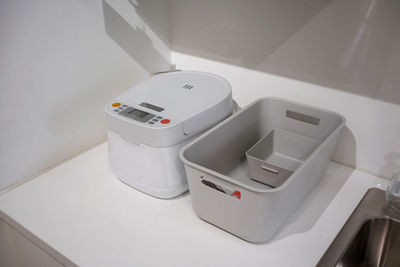 High angle view of rice cooker with containers on table