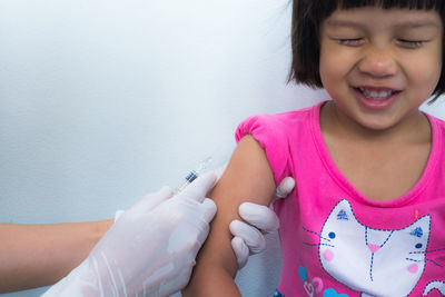 Cropped hands of doctor injecting girl at hospital