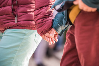 Midsection of couple holding hands outdoors