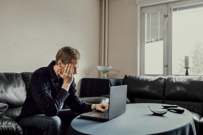 Man sitting on sofa and using laptop