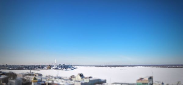 View of city by sea against clear blue sky