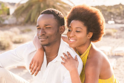 Happy young couple looking away while sitting outdoors