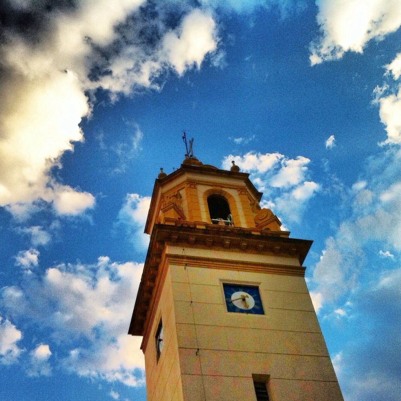 low angle view, religion, architecture, building exterior, church, built structure, place of worship, sky, spirituality, clock tower, cloud - sky, cross, tower, cathedral, cloud, blue, high section, clock