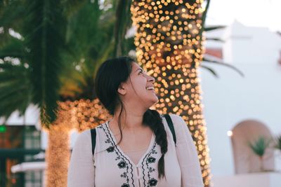 Happy woman against illuminated trees