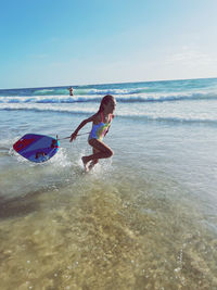 Rear view of boy playing in sea against sky