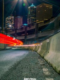 Light trails on street amidst buildings in city at night