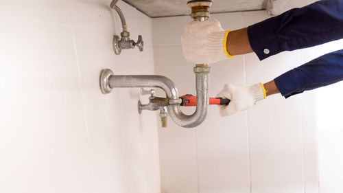 Close-up of hand holding faucet in bathroom