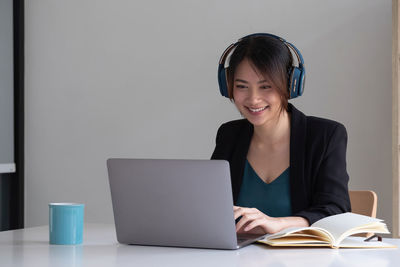 Young woman using phone while sitting on table
