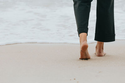 Low section of woman standing at beach