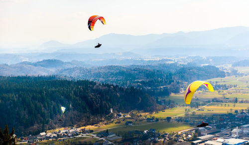 People paragliding over mountains against sky