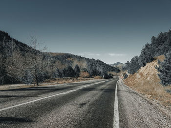 Empty road along trees and against sky