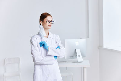 Full length of young woman standing against white wall