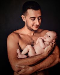 Portrait of father with baby against black background