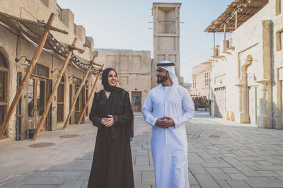 Smiling couple talking while walking on street in town