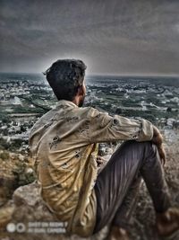 Rear view of man looking at sea against sky