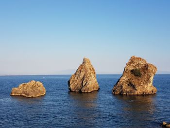 Panoramic view of rocks in sea against clear blue sky