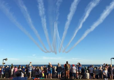 People looking at airshow over sea