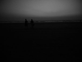 Silhouette people on beach against sky during sunset