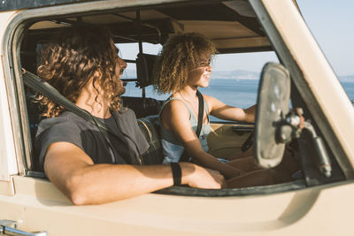 Man looking at woman driving car at beach