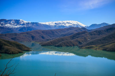 Scenic view of lake and mountains against blue sky