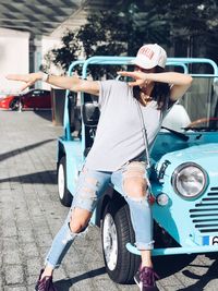 Woman posing by car during sunny day