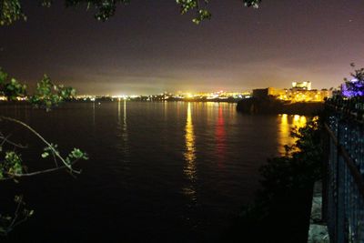 River by illuminated trees against sky