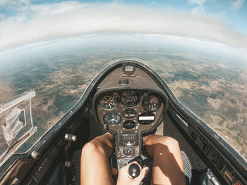 Low section of person in helicopter flying over landscape