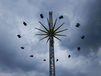 Low angle view of chain swing ride against sky