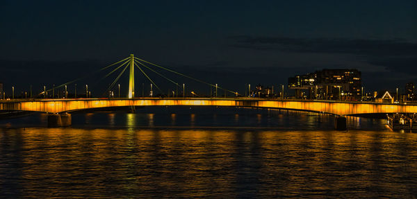 Illuminated bridge over river at night