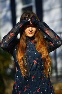 Portrait of young woman shielding eyes on sunny day