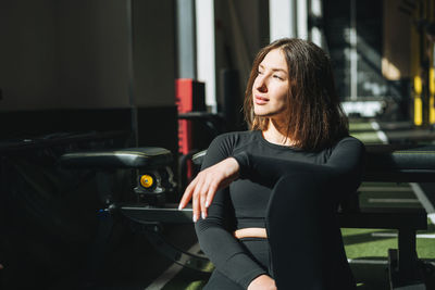 Portrait of resting young brunette woman in sport active wear in fitness club