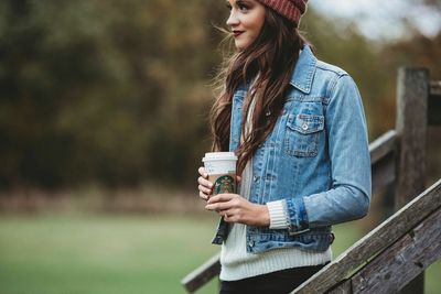 Portrait of smiling young woman standing against tree