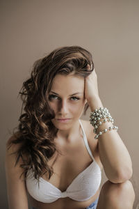 Portrait of beautiful young woman sitting against colored background