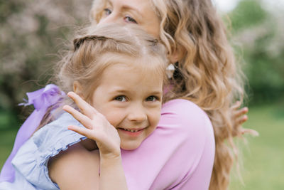 Happy girl daughter in her mother's arms in the park