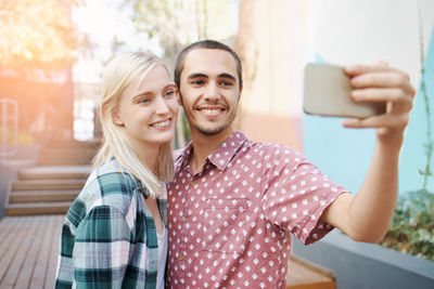 Smiling man taking selfie with girlfriend