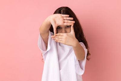 Portrait of young woman against pink background