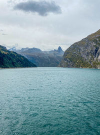 Scenic view of sea by mountains against sky