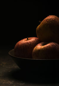 Close-up of bananas in bowl on table against black background