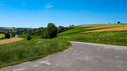 Road amidst field against sky