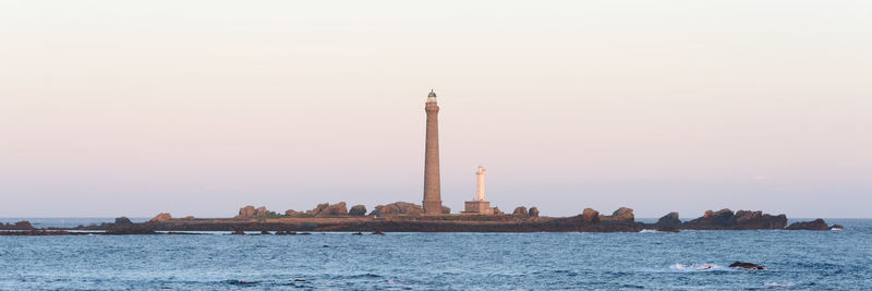 Lighthouse on sea against buildings